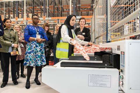 Garment worker demonstrating a machine at Boohoo model factory, Leicester